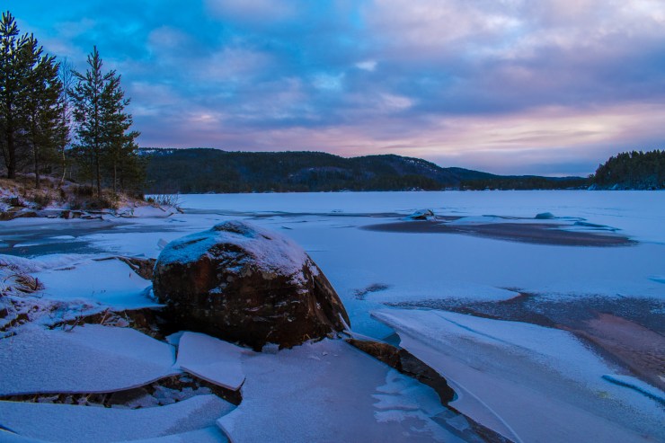 Blue hour photo of a frozen lake in Norway, Ice has broken around the rock.